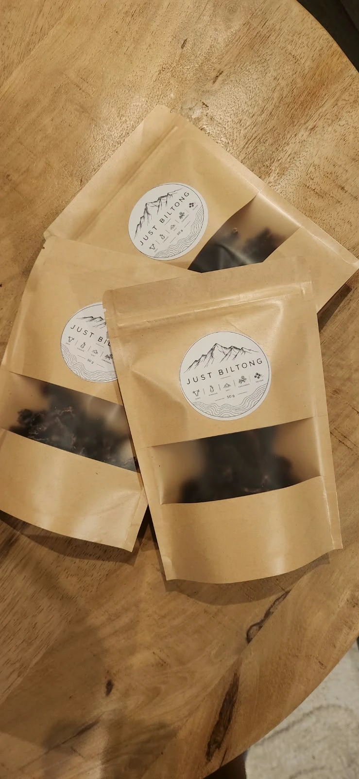 Three real Just Biltong bags on a wooden table